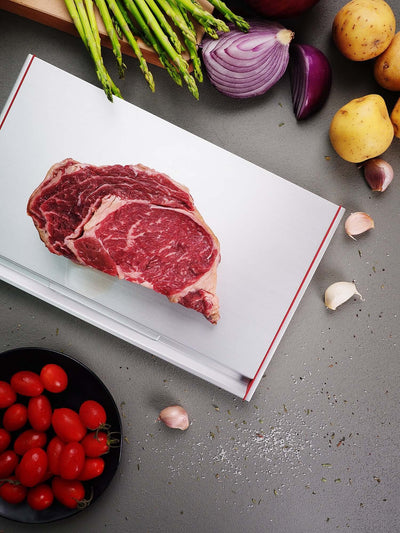 Defrosting steak on ThawTHAT! Modern board with vegetables, showcasing quick defrost innovation and sleek design.